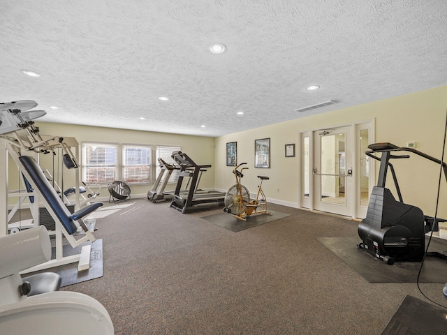 exercise room with carpet flooring and a textured ceiling