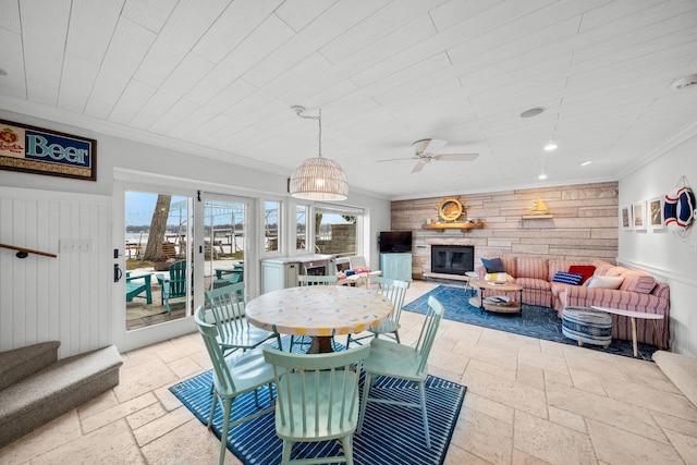 dining room with a stone fireplace, stone tile floors, a wealth of natural light, and crown molding