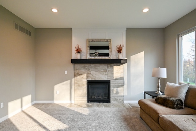 living room featuring a tile fireplace and carpet floors