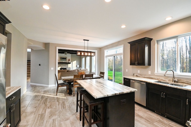 kitchen featuring stainless steel dishwasher, a center island, a healthy amount of sunlight, and sink