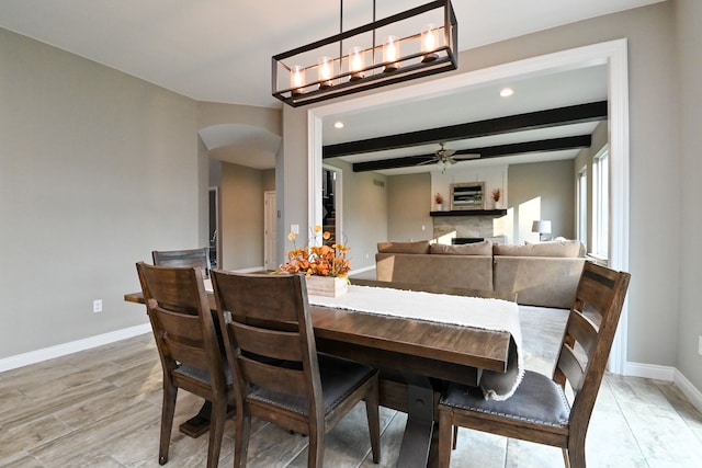 dining space featuring ceiling fan with notable chandelier, beam ceiling, and light hardwood / wood-style flooring