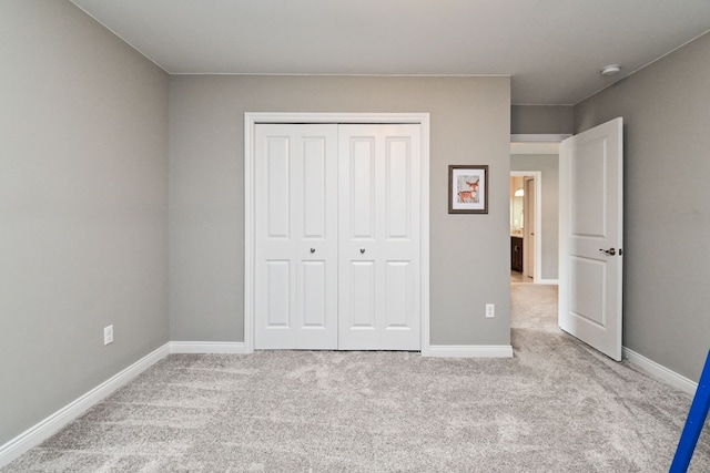 unfurnished bedroom with a closet and light colored carpet