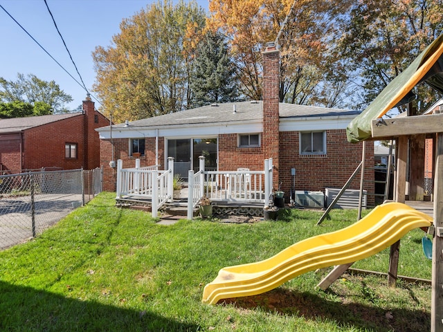 back of property featuring a yard and a playground