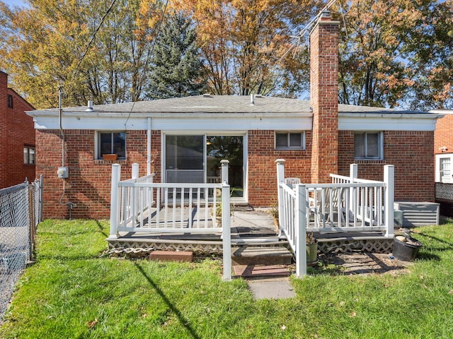 rear view of house with a lawn and a wooden deck