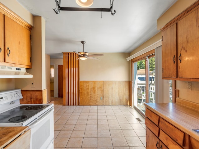 kitchen featuring white range with electric cooktop, ceiling fan, wood walls, and light tile patterned floors