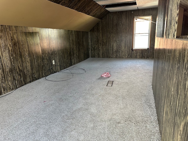 additional living space featuring carpet flooring, wood walls, and lofted ceiling