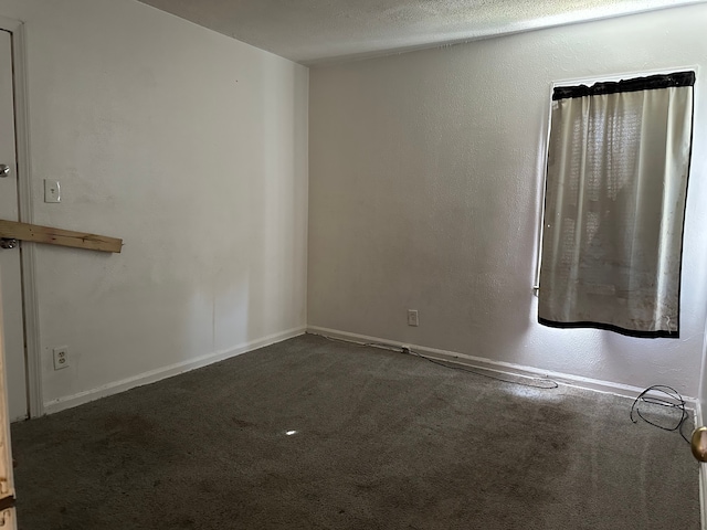 unfurnished room with dark carpet and a textured ceiling