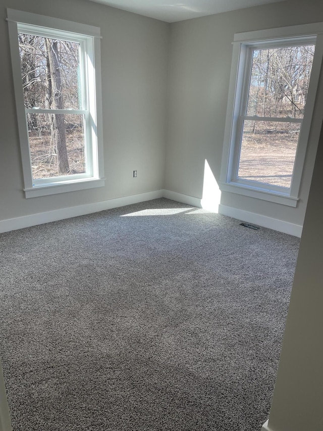 empty room with visible vents, baseboards, and carpet