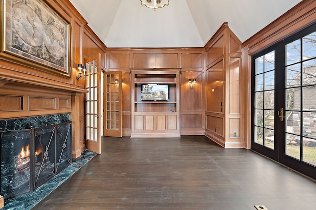 unfurnished living room with high vaulted ceiling, french doors, dark wood-type flooring, and a decorative wall