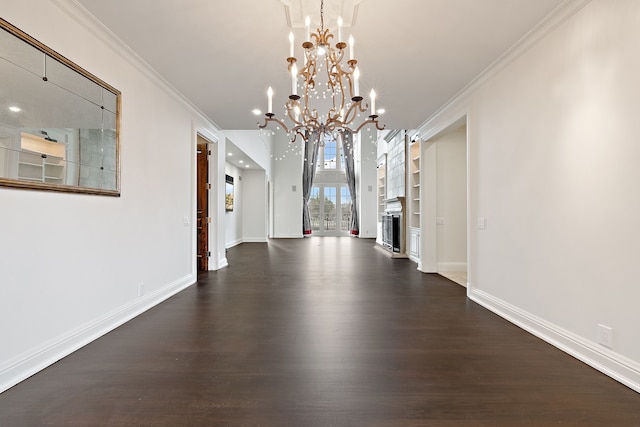 unfurnished dining area with dark wood-style floors, built in shelves, crown molding, an inviting chandelier, and baseboards