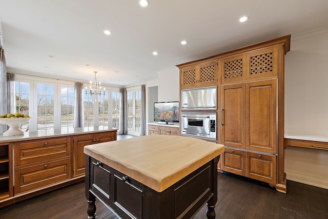 kitchen featuring dark wood-style floors, ornamental molding, decorative light fixtures, and a center island