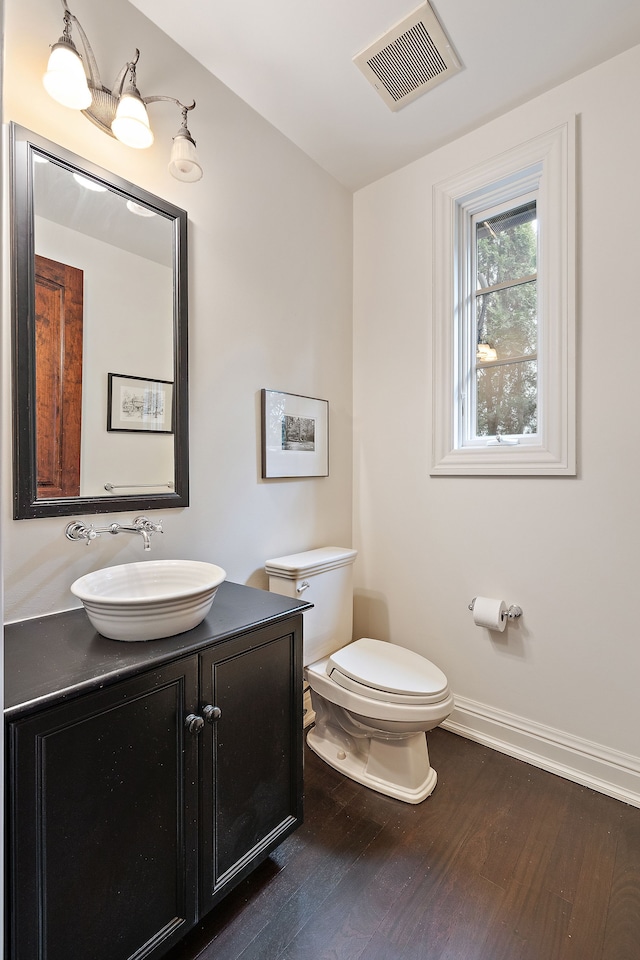 bathroom with toilet, wood finished floors, vanity, visible vents, and baseboards