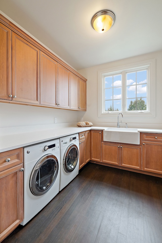 clothes washing area featuring dark wood-style flooring, washer and clothes dryer, a sink, and cabinet space