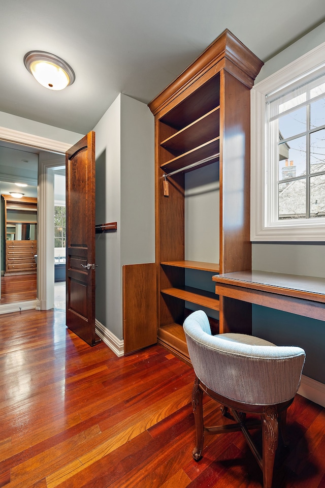 home office featuring baseboards, wood finished floors, built in study area, and a healthy amount of sunlight