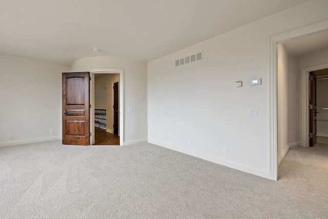 empty room featuring light carpet, baseboards, and visible vents