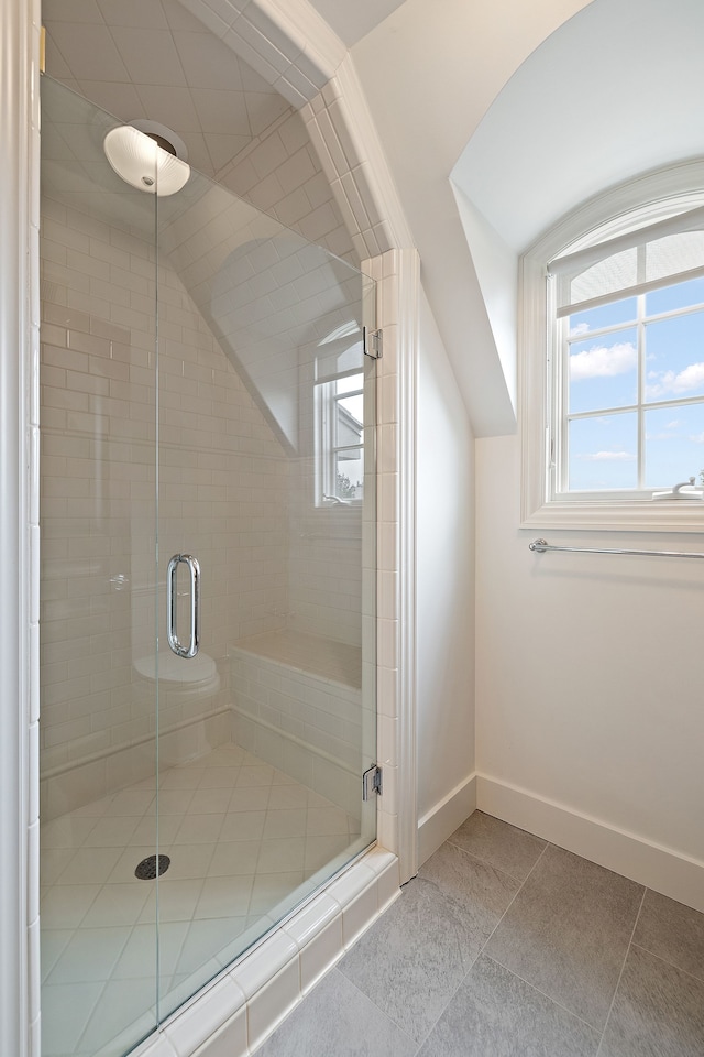 full bath featuring a stall shower, tile patterned flooring, vaulted ceiling, and baseboards