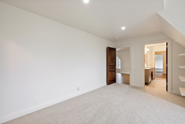 unfurnished bedroom with recessed lighting, light carpet, baseboards, and ensuite bathroom