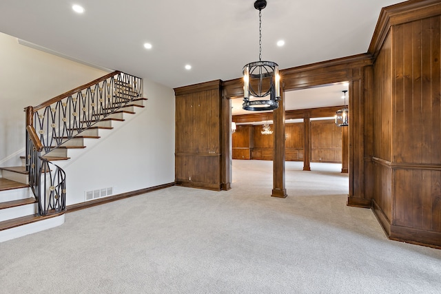 unfurnished dining area with recessed lighting, light colored carpet, visible vents, stairway, and wooden walls