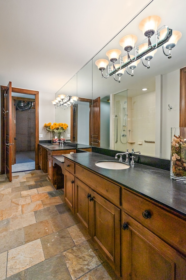 full bathroom featuring stone tile flooring, a shower stall, and vanity