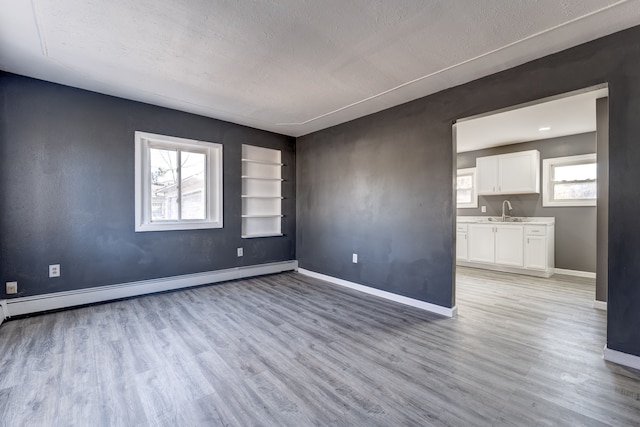 empty room featuring plenty of natural light, light hardwood / wood-style floors, and a baseboard radiator