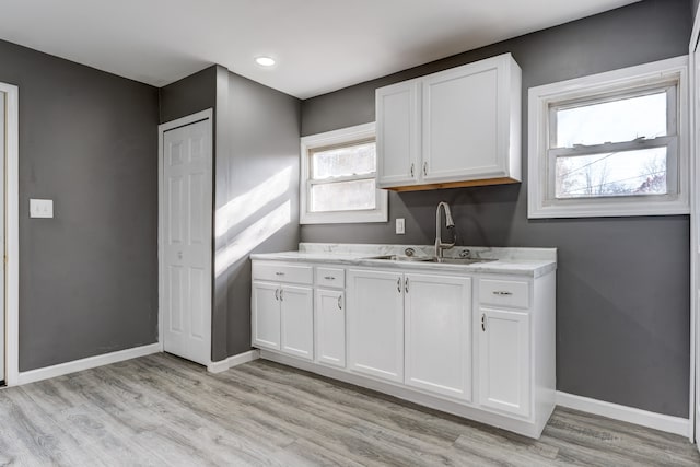 kitchen featuring white cabinets, light hardwood / wood-style flooring, and sink