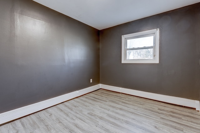 unfurnished room with baseboard heating and light hardwood / wood-style flooring