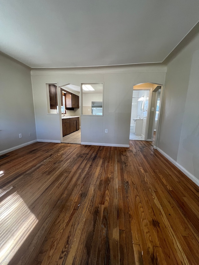 unfurnished living room featuring a healthy amount of sunlight, sink, and dark wood-type flooring