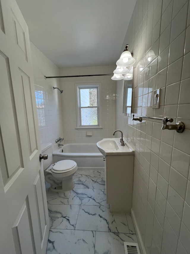 full bathroom with tiled shower / bath, vanity, tile walls, and toilet