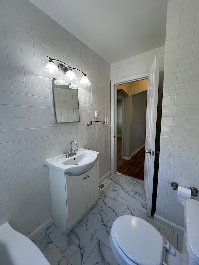 bathroom featuring vanity, toilet, and tile walls