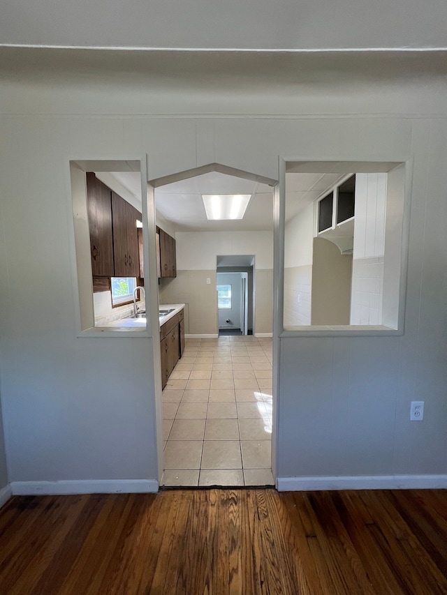 kitchen with dark brown cabinets, light wood-type flooring, and sink