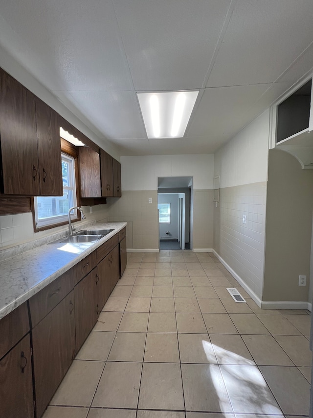 kitchen featuring light tile patterned flooring, dark brown cabinetry, and sink