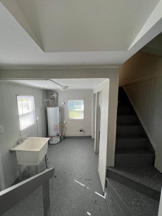 interior space with wooden walls, sink, a healthy amount of sunlight, and gas water heater