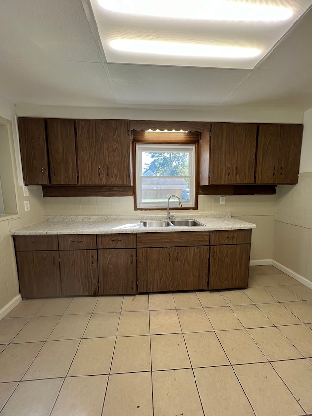 kitchen featuring light tile patterned flooring, dark brown cabinetry, and sink