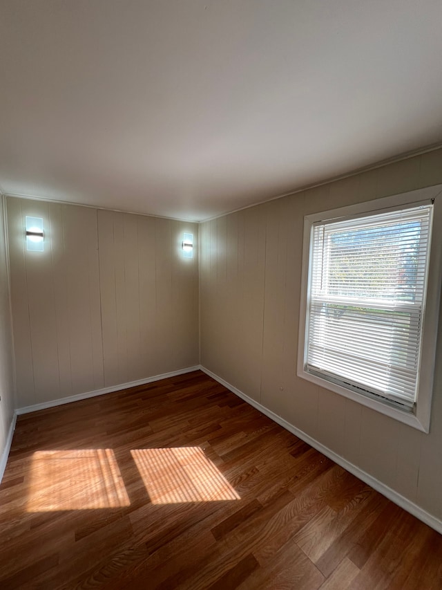 spare room featuring hardwood / wood-style floors and wooden walls