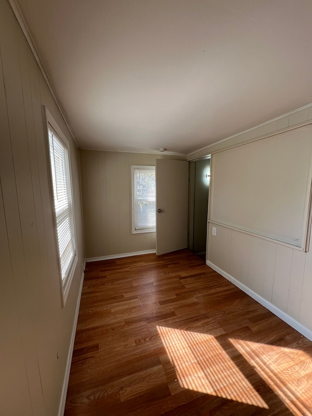 spare room featuring wooden walls, dark hardwood / wood-style flooring, and crown molding