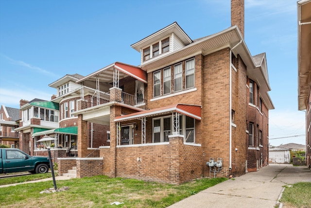 view of front of home with a balcony and a front yard