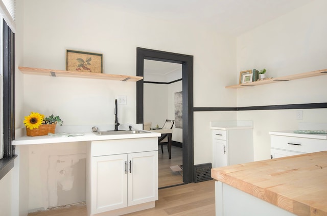 kitchen with white cabinets, sink, and light hardwood / wood-style flooring