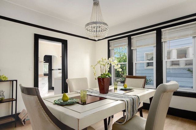 dining space with light hardwood / wood-style flooring and a chandelier