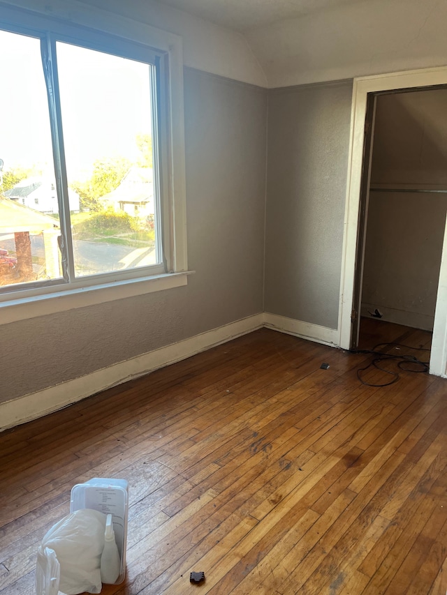 unfurnished bedroom with hardwood / wood-style floors and lofted ceiling