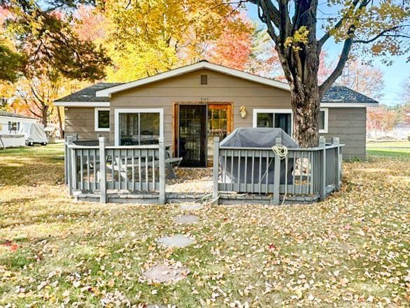 back of property with a yard and a wooden deck