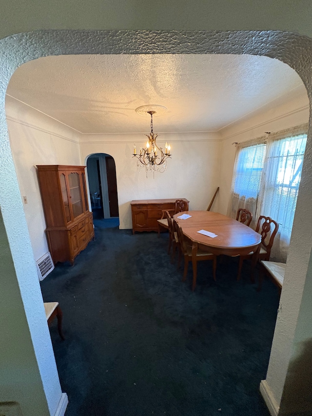 dining area featuring a chandelier, dark carpet, and a textured ceiling