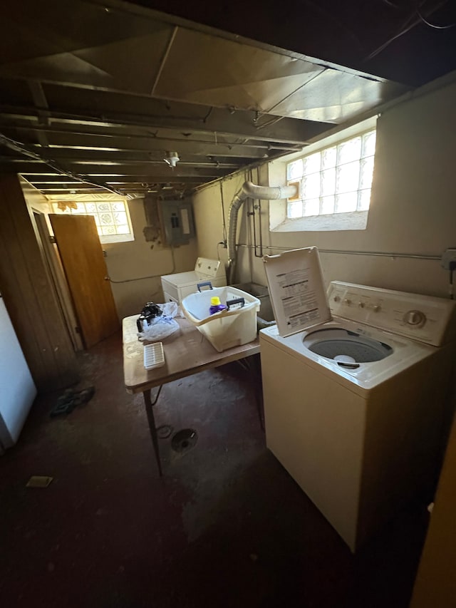 basement featuring a wealth of natural light, electric panel, and washer and clothes dryer