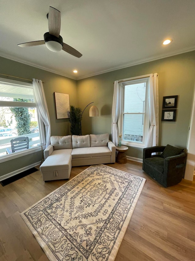 living room with light hardwood / wood-style floors, ceiling fan, and ornamental molding