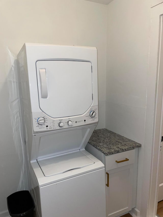 laundry room with stacked washer and dryer and cabinets