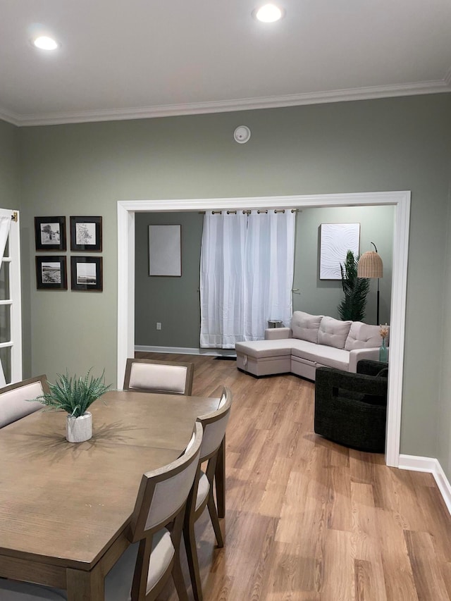 dining room with crown molding and light hardwood / wood-style flooring