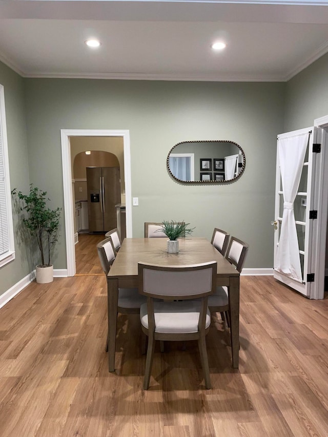 dining area with wood-type flooring and ornamental molding