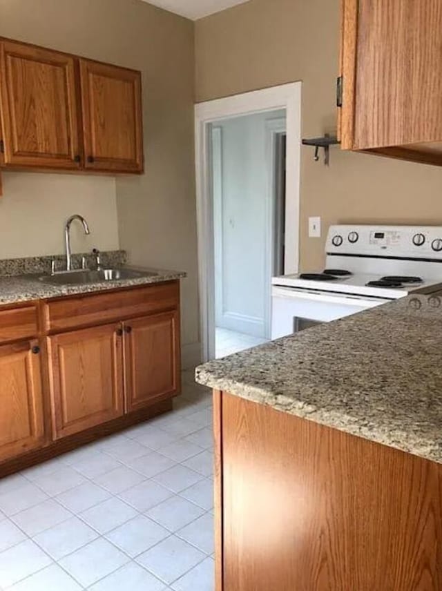 kitchen featuring light stone countertops, sink, light tile patterned floors, and white electric stove