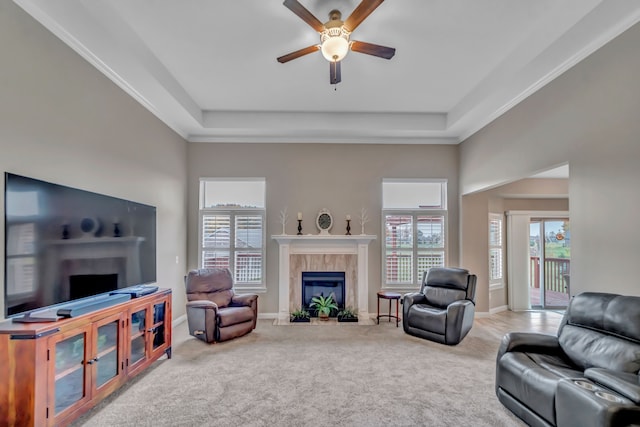 carpeted living room featuring a tray ceiling, ceiling fan, and a healthy amount of sunlight