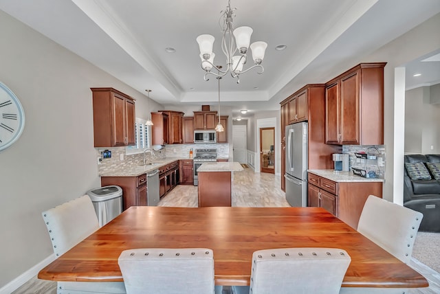 dining area featuring a raised ceiling, sink, light hardwood / wood-style flooring, and an inviting chandelier