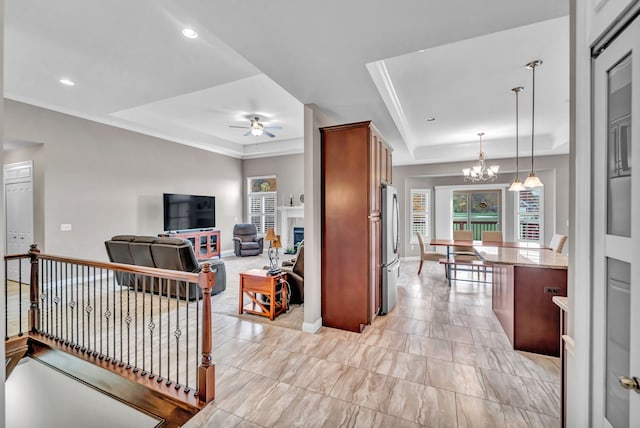 living room with a tray ceiling and ceiling fan with notable chandelier